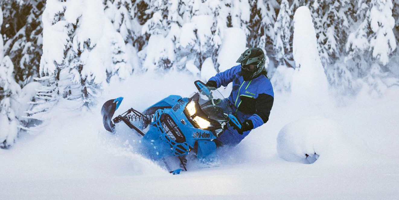 Rider carves in deep powder with a blue snowmobile